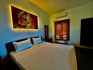 a bedroom with a large bed with a painting on the wall at Whisky Point Surf Cabana in Arugam Bay