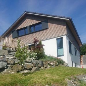 ein Haus auf einem Hügel mit einer Steinmauer in der Unterkunft Ferienwohnung Astis in Blaichach