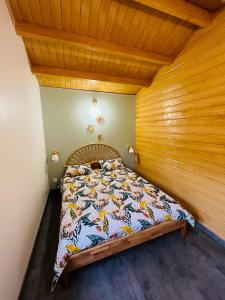 Bett in einem Zimmer mit einer Holzwand in der Unterkunft Chalet bord de l'eau avec spa privatif in Longpré-les-Corps-Saints