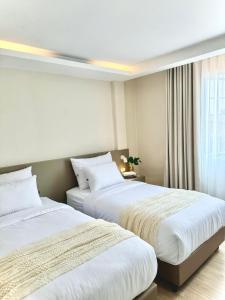 een hotelkamer met 2 bedden en een raam bij สุขใจแกรนด์ in Loei