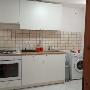 a kitchen with white cabinets and a washing machine at Scario house in Scario