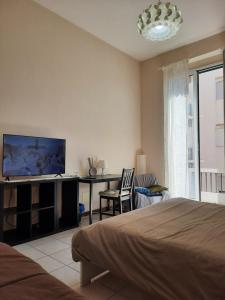 a bedroom with a bed and a desk with a flat screen tv at Casa Messina Inn in Messina