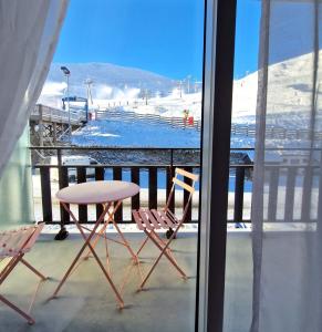 einen Tisch und Stühle auf einem Balkon mit einem schneebedeckten Berg in der Unterkunft LeChalet N22 Au pied des pistes in Saint-Lary-Soulan