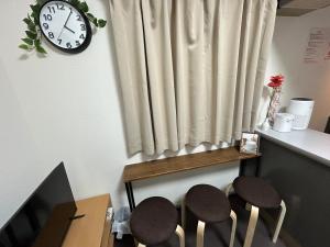 Zimmer mit zwei Hockern und einer Uhr an der Wand in der Unterkunft Guest House Raffine HAKATA in Fukuoka