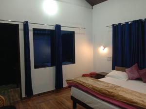 een slaapkamer met een bed en twee ramen met blauwe gordijnen bij Lake Haven Resort, Sari, Chopta in Sari