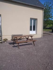 a picnic table sitting in front of a building at L établissement Gold Beach propose 1 maison 80m2 avec terrain 500m2 PARKING PRIVE à 4 min du port artificiel d ARROMANCHES SERVICES Accueil personnalisé lits faits serviettes ménage NETFLIX wifi SUR VELOROUTE in Ryes