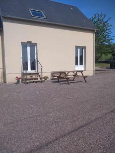 a picnic table and bench in front of a building at L établissement Gold Beach propose 1 maison 80m2 avec terrain 500m2 PARKING PRIVE à 4 min du port artificiel d ARROMANCHES SERVICES Accueil personnalisé lits faits serviettes ménage NETFLIX wifi SUR VELOROUTE in Ryes