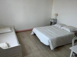 a bedroom with two beds and a wooden floor at Charmante maison landaise in Soustons
