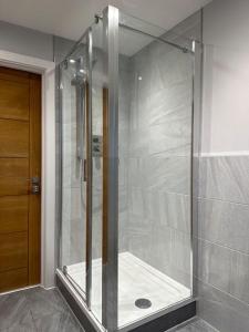 een douche met een glazen deur in de badkamer bij Modern, spacious with s/king bed Apartment in Brentwood