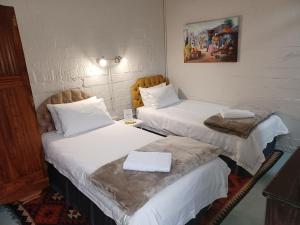2 camas en una habitación de hotel con sábanas blancas en 19 on Robyn en Durbanville