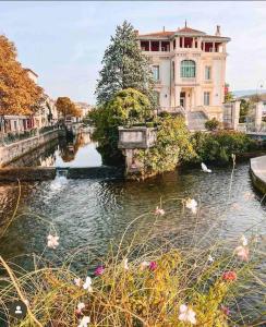 a building and a river with birds in the water at La loge familiale: 110m2, place rose goudard, AC in LʼIsle-sur-la-Sorgue