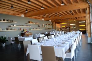 una lunga sala da pranzo con tavoli e sedie bianchi di Tocchi di Puglia a Castellaneta Marina