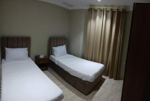 2 camas en una habitación pequeña con cortinas en ماجيك سويت الرقعى Magic Suite AlRaggi en Kuwait
