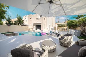 a patio with an umbrella and chairs and a pool at Luxurious Villa, Private Pool and Garden, Dubai in Dubai