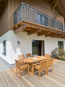 uma mesa de madeira e cadeiras num deque com uma varanda em Wohlfühlchalet Hermagor-Nassfeld-Weissensee em Hermagor