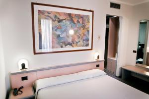 1 dormitorio con 1 cama y una pintura en la pared en Ilga Hotel, en Collecchio