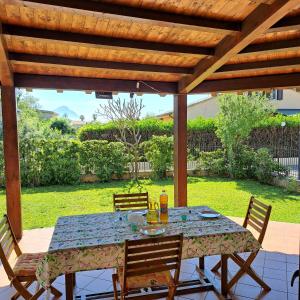 a table and chairs under a wooden pergola at Tusa Appartavilla Residence le Case del sole Campofelice di Roccella in Campofelice di Roccella +36 photos