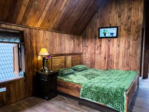 ein Schlafzimmer mit einem Bett mit einer Holzwand in der Unterkunft Vườn Hoa Măng Đen Village in Kon Plong