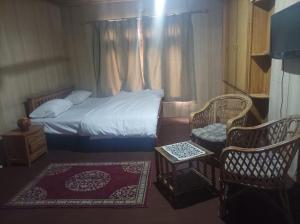 ein kleines Schlafzimmer mit einem Bett und zwei Stühlen in der Unterkunft Baltistan guest house in Skardu