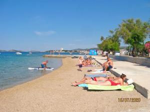 a group of people laying on towels on a beach at Villa Aurelia Vodice in Vodice