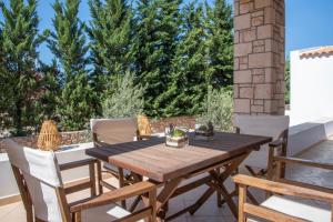 una mesa de madera y sillas en un patio con árboles en Katrin Aegina, en Aegina Town