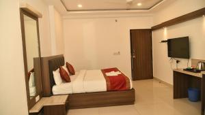 Schlafzimmer mit einem Bett und einem Flachbild-TV in der Unterkunft Hotel MM Continental in Varanasi
