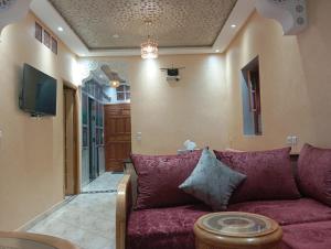 a living room with a purple couch and a tv at Maison Moussaoui in Meknès