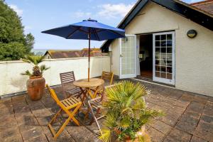 a table and chairs with an umbrella on a patio at Vale View Apartment in Porlock