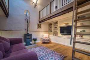ein Wohnzimmer mit einem lila Sofa und einem TV in der Unterkunft The Cowshed in Clatworthy