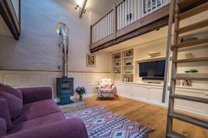 a living room with a purple couch and a tv at The Cowshed in Clatworthy