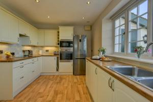 a kitchen with white cabinets and stainless steel appliances at Coach House in Washford