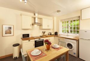 una cucina con mobili bianchi e un tavolo di legno di Worthy Cottage a Porlock Altre 8 foto
