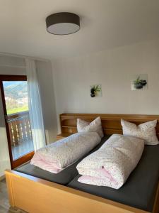 Bett mit Kissen und Fenster in der Unterkunft Ferienhof Brutoni in Bad Peterstal-Griesbach