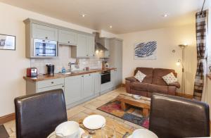 a kitchen and living room with a couch and a table at The Stable Block, Porlock Weir in Porlock