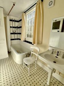 ein Badezimmer mit einer Badewanne, einem Waschbecken und einem Stuhl in der Unterkunft Orchard Cottage in Charles
