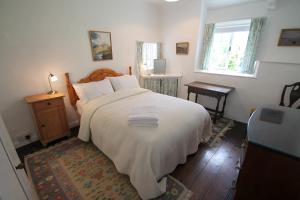 a bedroom with a large white bed and a window at Ball Cottage in Winsford