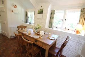 uma mesa de madeira numa sala de jantar com cadeiras e janelas em Ball Cottage em Winsford