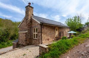 a small brick building with a chimney on a road at The Mill House in Bampton