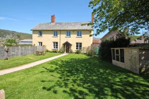 una grande casa con un cortile verde con una recinzione di Farm Cottage, West Luccombe a Porlock