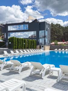 a pool with white lounge chairs and a building at Avalon Hotel&Pool in Yelikhovichi