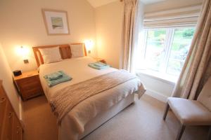 a bedroom with a large bed with a window at Magnolia Cottage in Porlock