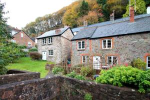 an old stone house with a garden in front of it at Magnolia Cottage in Porlock