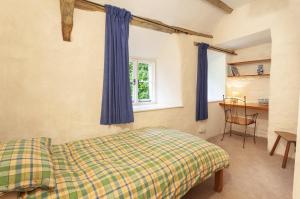 a bedroom with a bed and a window with blue curtains at Old Church House, Brayford in Highbray