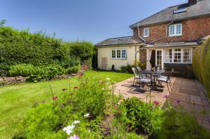 a patio with a table and chairs in a garden at Jacobs Pond, Near Monksilver in Stogumber