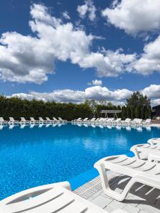 a large swimming pool with white chairs and blue skies at Avalon Hotel&Pool in Yelikhovichi