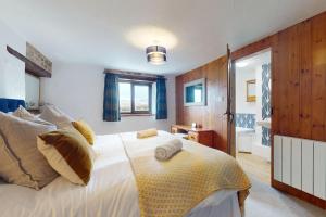 um quarto com uma grande cama branca e uma casa de banho em Jasper Cottage Hawkridge em Dulverton