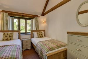 2 Betten in einem kleinen Zimmer mit Spiegel in der Unterkunft The Shippon in Wheddon Cross