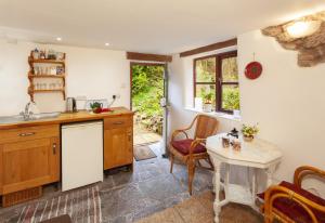 Garden Cottage, Wiveliscombe في Wiveliscombe: مطبخ مع حوض وطاولة مع كراسي