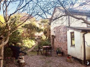 Garden Cottage, Wiveliscombe في Wiveliscombe: حديقة صغيرة بها طاولة ومبنى