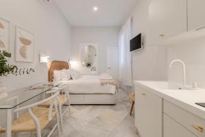 um quarto branco com uma cama e uma cozinha em Indulge Group: Downtown Cuna 1.0 em Sevilha